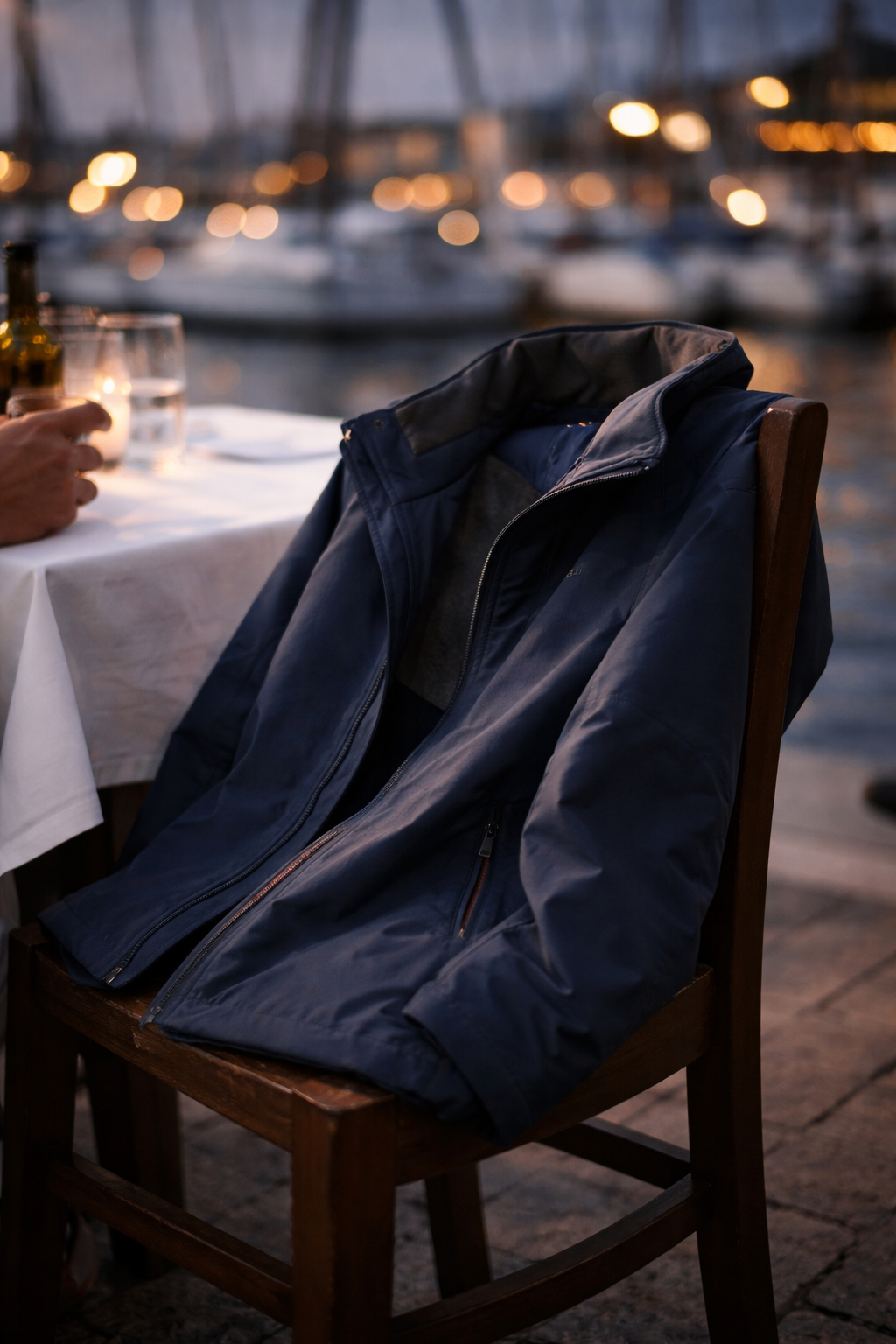The Crossing Jacket draped over a chair at a harbourside restaurant